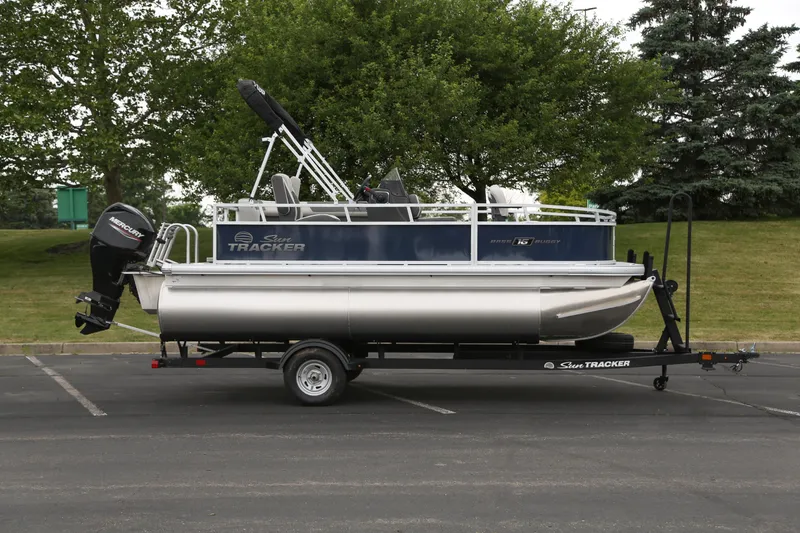 The Image of 2026 Sun Tracker Bass Buggy 16 XL Select pontoon boat on trailer in parking lot. - 0