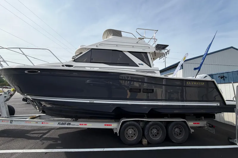 The Image of 2026 Cutwater C-288 CB boat on trailer, sleek design, parked outdoors. - 1