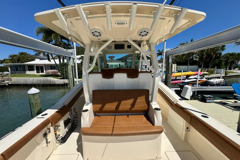Slide: The Image of 2018 Scout 355 LXF boat interior with seating, docked by waterfront homes. - 11