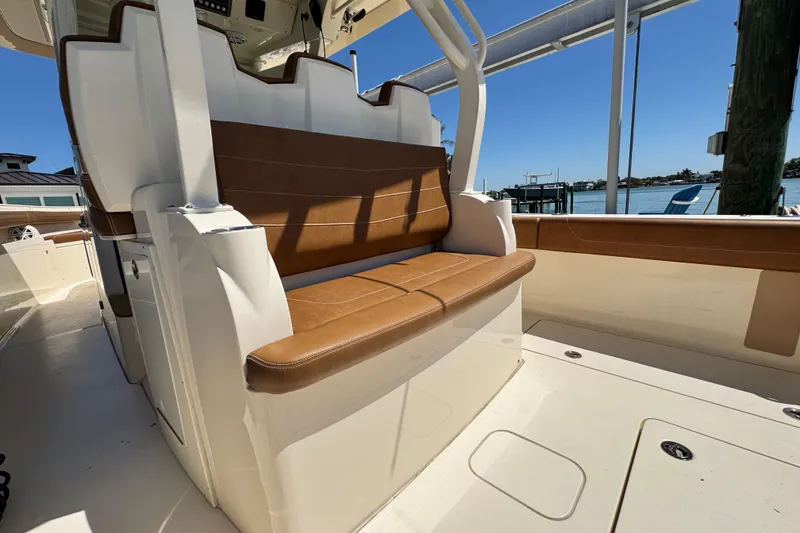 Slide: The Image of 2018 Scout 355 LXF boat interior with brown leather seating, dockside view. - 13