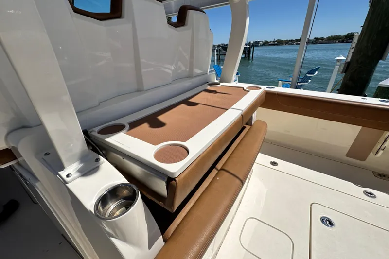 Slide: The Image of 2018 Scout 355 LXF boat interior with seating and cup holders by the water. - 14