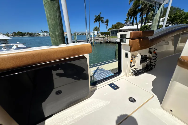 Slide: The Image of 2018 Scout 355 LXF boat interior with tan seating, dockside view, and clear blue sky. - 16