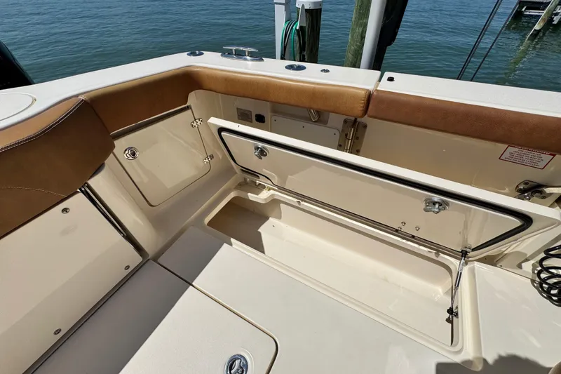 Slide: The Image of 2018 Scout 355 LXF boat interior with open storage compartment by the water. - 18