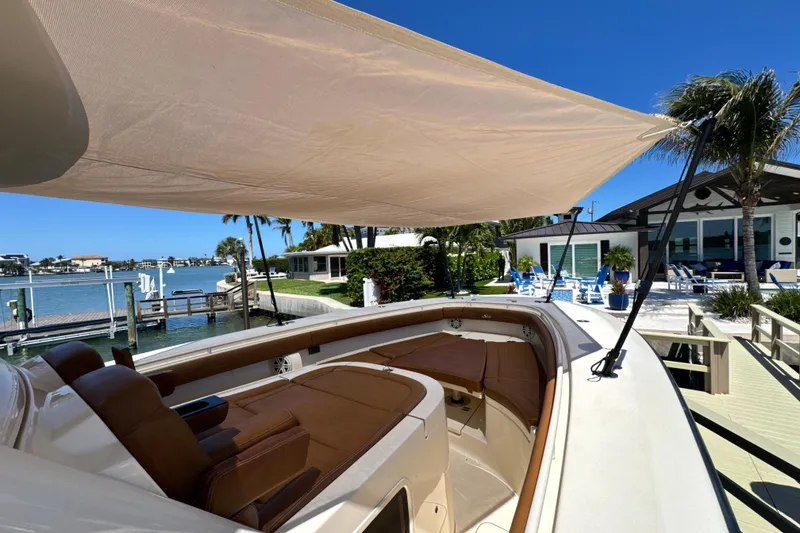 Slide: The Image of 2018 Scout 355 LXF boat docked by waterfront home, featuring sunshade and luxurious seating. - 28