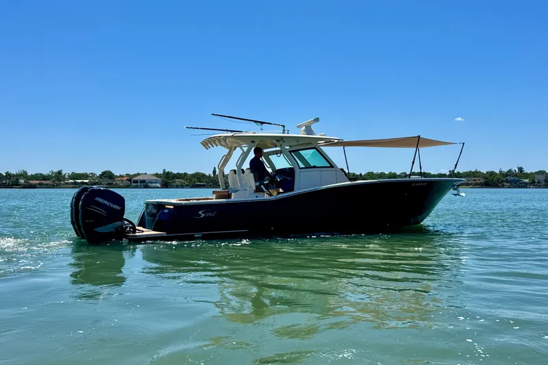 Slide: The Image of 2018 Scout 355 LXF boat on calm water under clear blue sky. - 3