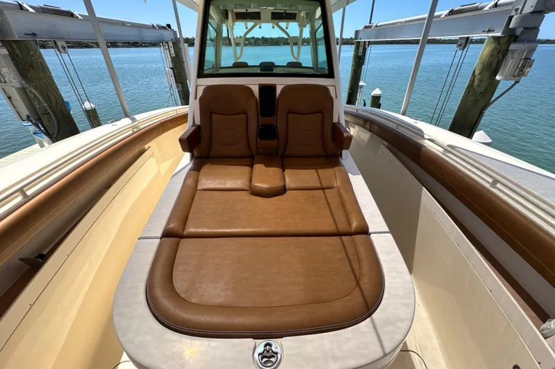 Slide: The Image of 2018 Scout 355 LXF boat with luxurious brown seating, docked by the water. - 30