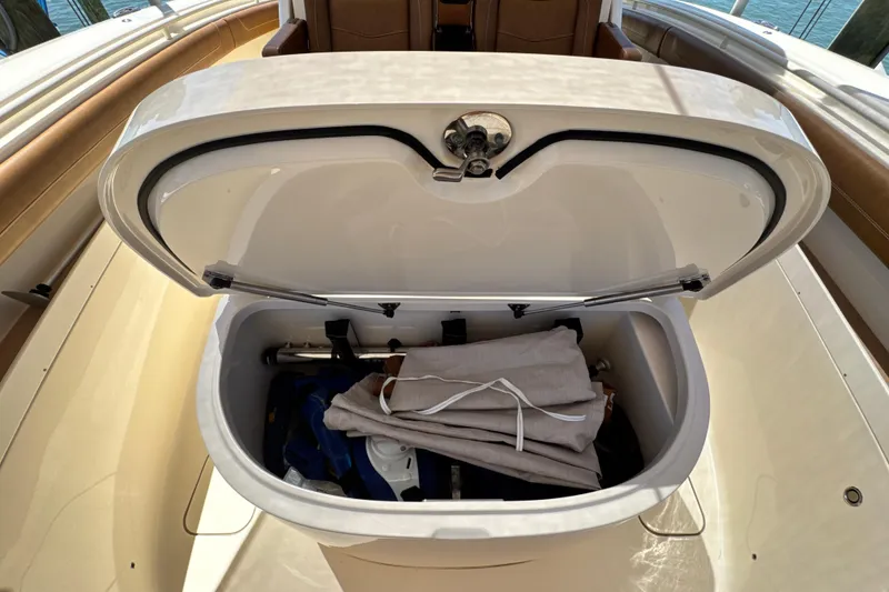 Slide: The Image of Open storage compartment on 2018 Scout 355 LXF boat, containing folded canvas and equipment. - 31
