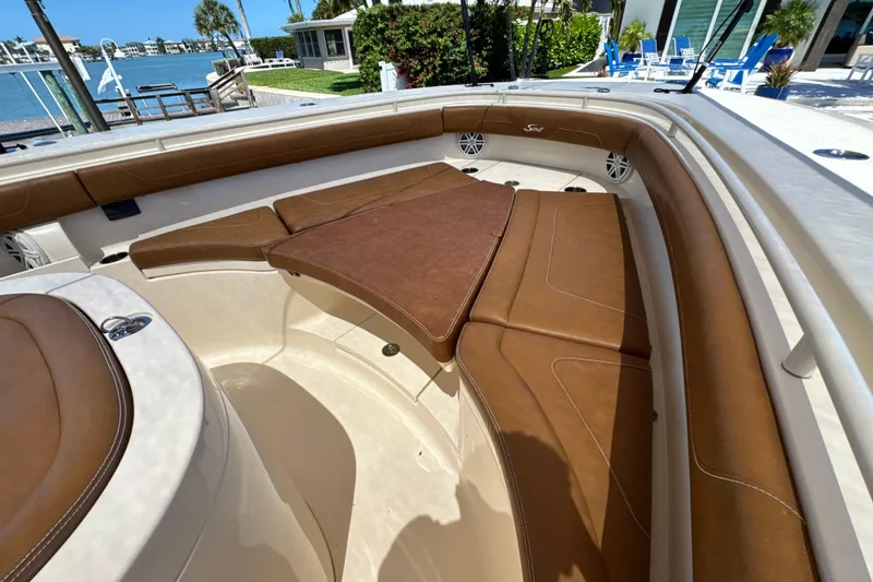 Slide: The Image of 2018 Scout 355 LXF boat interior with brown leather seating and waterfront view. - 32