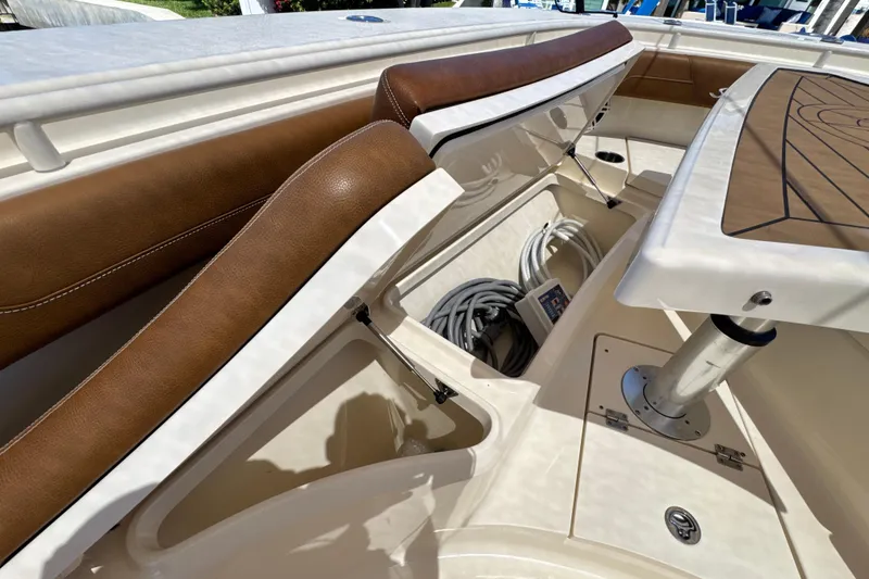 Slide: The Image of 2018 Scout 355 LXF boat interior with open storage compartment and brown seating. - 35