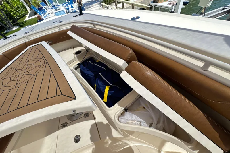Slide: The Image of 2018 Scout 355 LXF boat with open storage compartments and brown cushioned seating. - 36