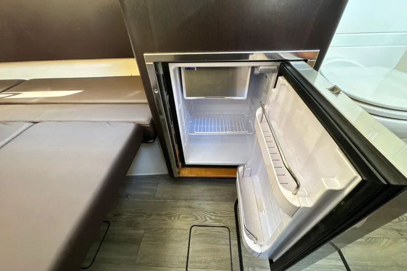 Slide: The Image of Open mini fridge inside 2018 Scout 355 LXF boat cabin, next to seating area. - 45