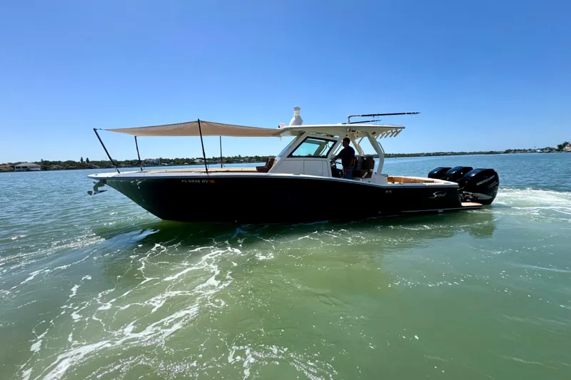 Slide: The Image of 2018 Scout 355 LXF boat cruising on a sunny day with canopy extended. - 5