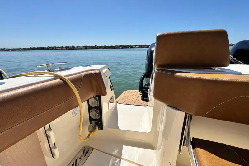 Slide: The Image of 2018 Scout 355 LXF boat interior with brown seating, overlooking calm waters. - 7