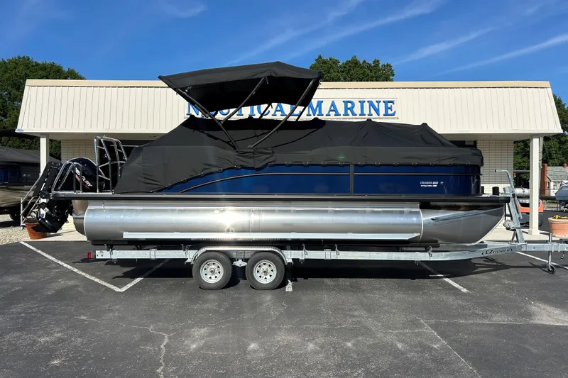 Slide: The Image of 2026 Harris Cruiser 230 CWDH pontoon boat on trailer, covered, outside marine dealership. - 20