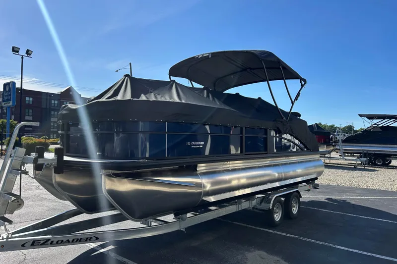 Slide: The Image of 2026 Harris Cruiser 230 CWDH pontoon boat on trailer under clear blue sky. - 22