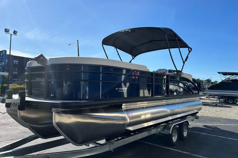 Slide: The Image of 2026 Harris Cruiser 230 CWDH pontoon boat on trailer, parked outdoors under clear sky. - 3