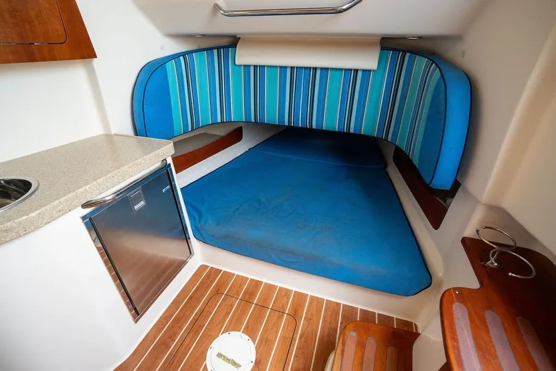 Slide: The Image of 2014 Grady-White Canyon 376 cabin interior with blue bedding and compact kitchenette. - 61