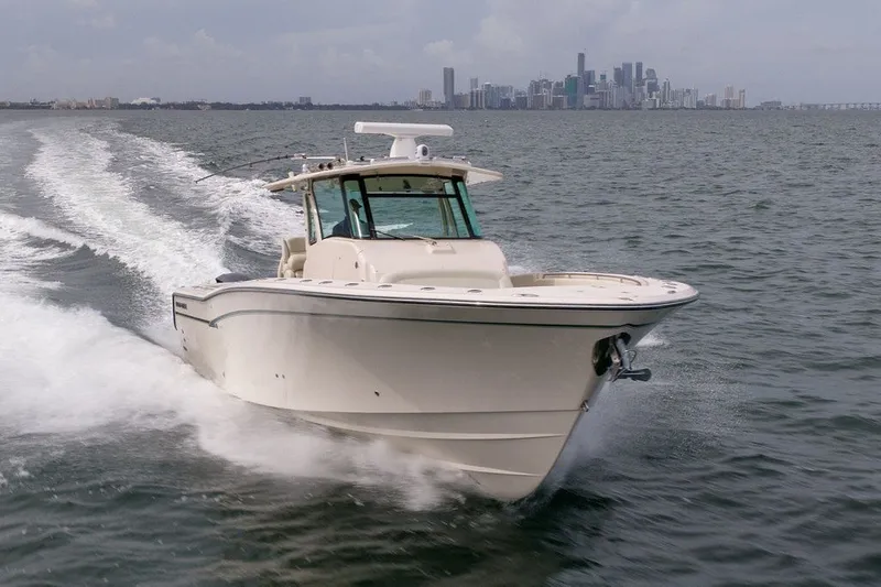 Slide: The Image of 2014 Grady-White Canyon 376 boat cruising on open water with city skyline backdrop. - 10