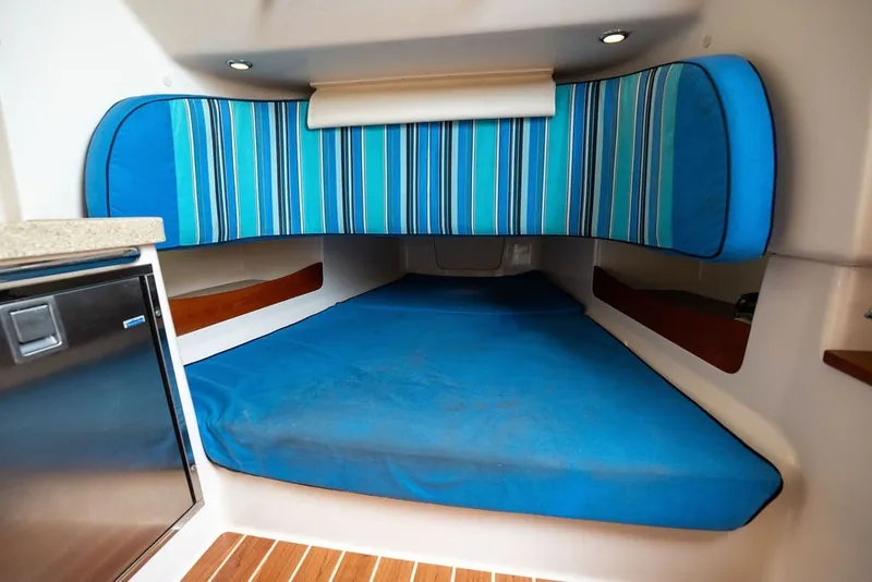 Slide: The Image of 2014 Grady-White Canyon 376 cabin interior with blue striped cushions and compact fridge. - 62