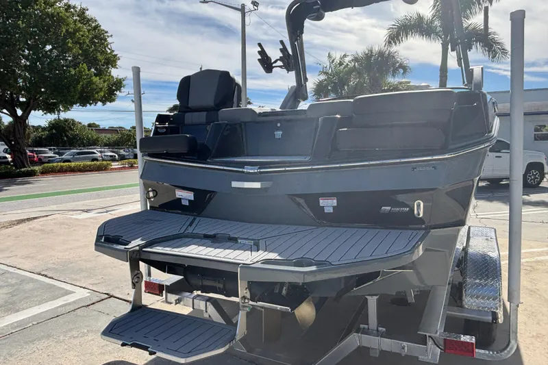 Slide: The Image of 2026 MasterCraft XT24 boat on trailer, rear view with swim platform, parked outdoors. - 2