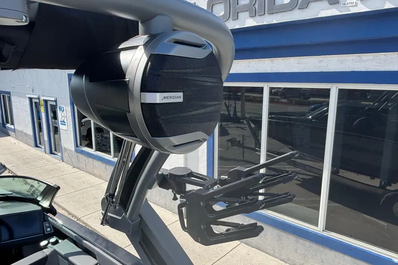 Slide: The Image of 2026 MasterCraft XT24 boat with Meridian speaker and wakeboard rack, parked outside a building. - 8