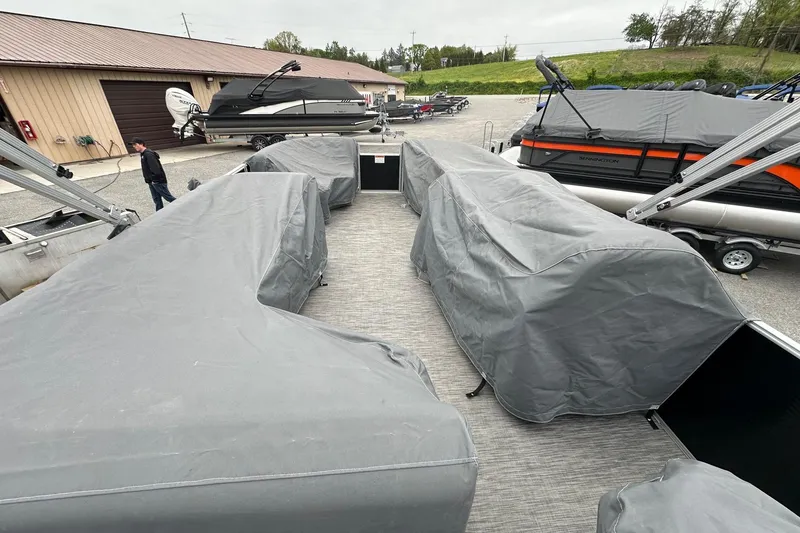 Slide: The Image of 2020 Bennington 20 SSNPX pontoon boat with covered seating, parked outdoors. - 21