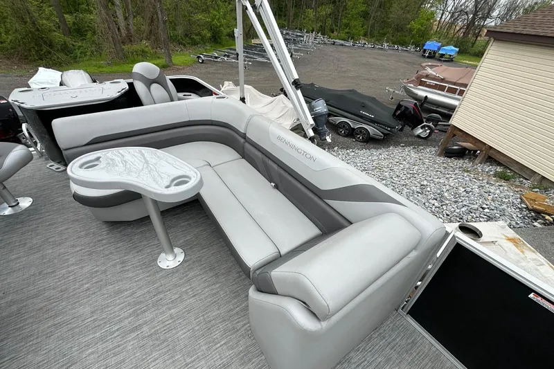 Slide: The Image of 2020 Bennington 20 SSNPX pontoon boat with gray seating and table, parked outdoors. - 9