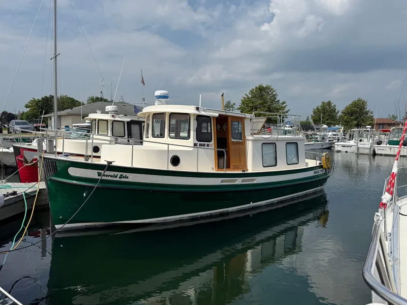 The Image of 1998 Nordic Tug Trawler docked in a marina under a cloudy sky. - 0