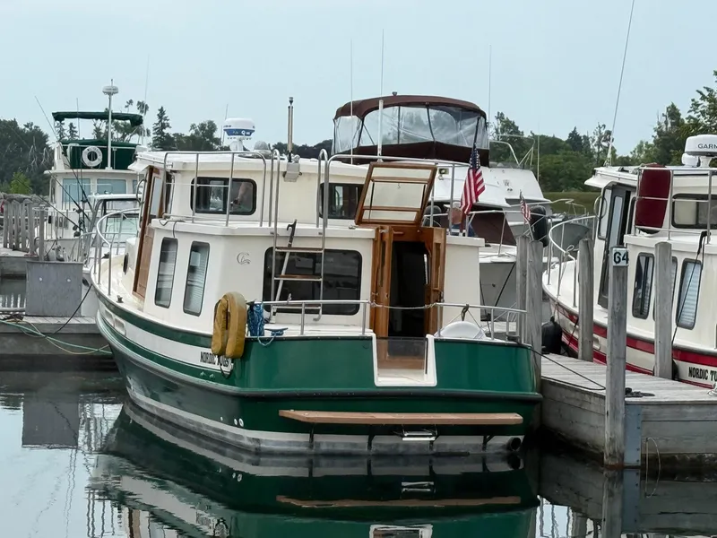 Slide: The Image of 1998 Nordic Tug Trawler docked at marina, surrounded by other boats. - 11