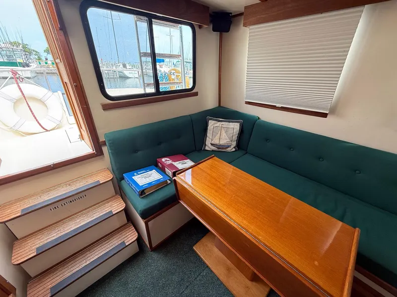 Slide: The Image of Cozy interior of 1998 Nordic Tug Trawler with green seating and wooden table. - 12