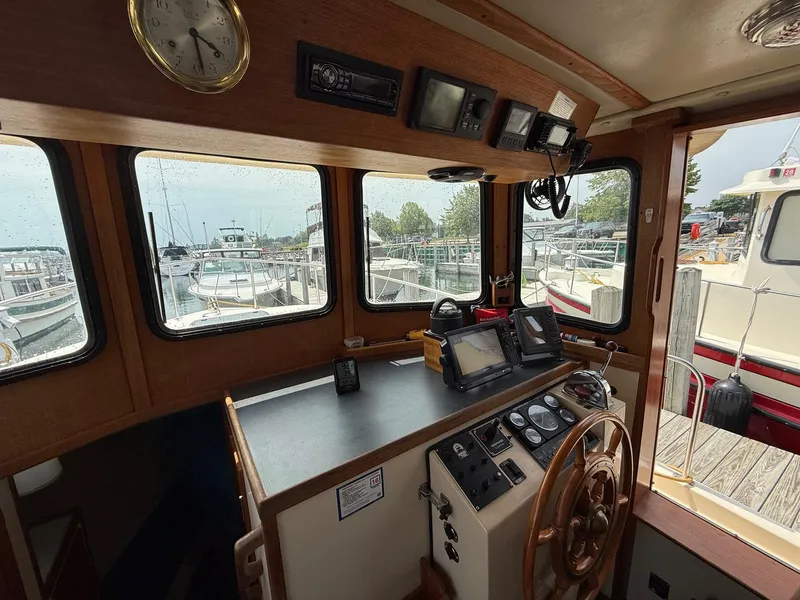 Slide: The Image of 1998 Nordic Tug Trawler helm with navigation equipment and wooden steering wheel, docked at marina. - 15