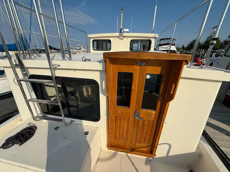 Slide: The Image of 1998 Nordic Tug Trawler with wooden doors and metal ladder, docked at marina. - 2