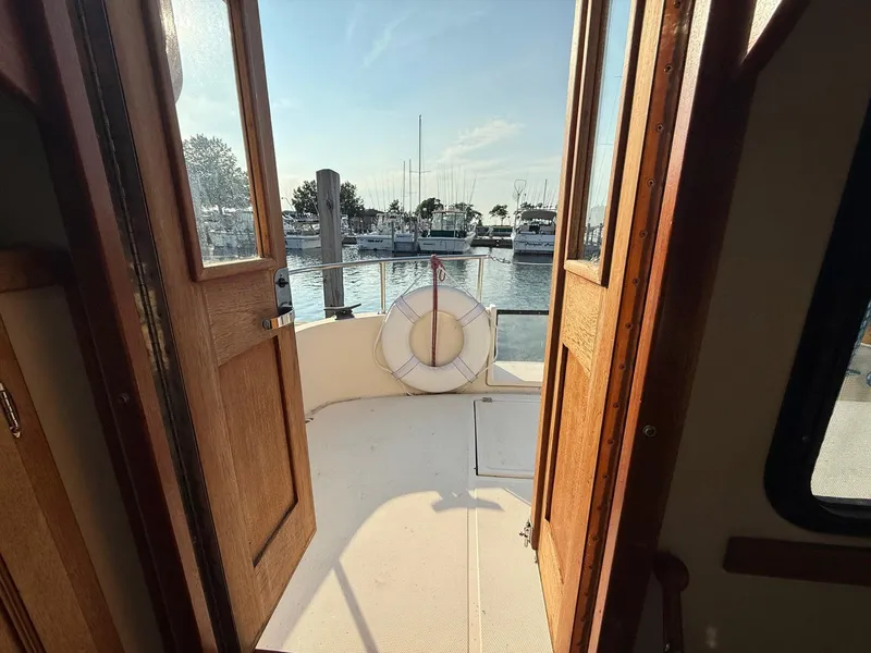 Slide: The Image of 1998 Nordic Tug Trawler deck view with open wooden doors and marina backdrop. - 4