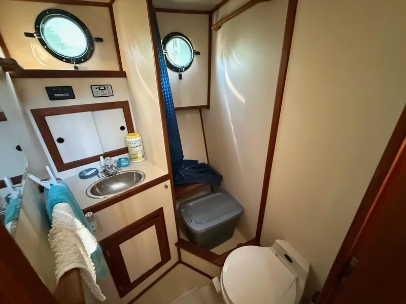 Slide: The Image of Bathroom interior of a 1998 Nordic Tug Trawler with sink, toilet, and porthole windows. - 6