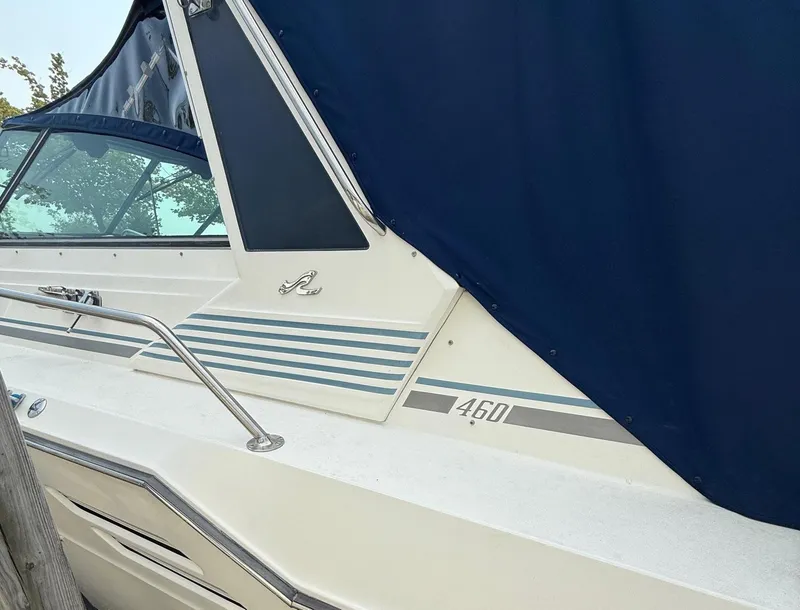 Slide: The Image of 1989 Sea Ray 460 Express Cruiser with blue canvas cover and sleek design. - 6