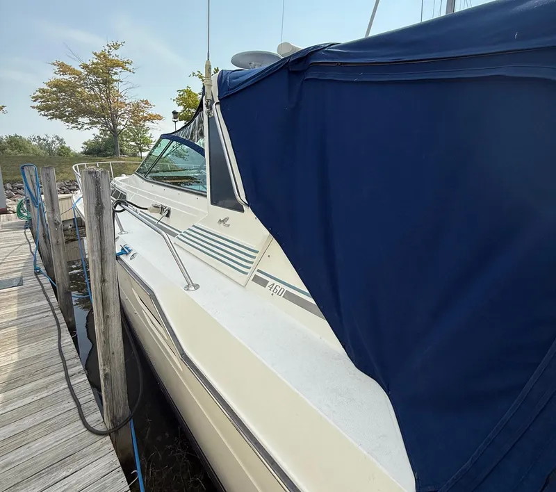 Slide: The Image of 1989 Sea Ray 460 Express Cruiser docked with blue cover, side view. - 8