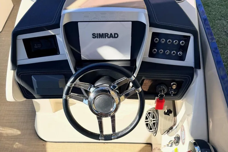 Slide: The Image of 2021 Harris Crowne SL 250 boat dashboard with Simrad display and steering wheel. - 14