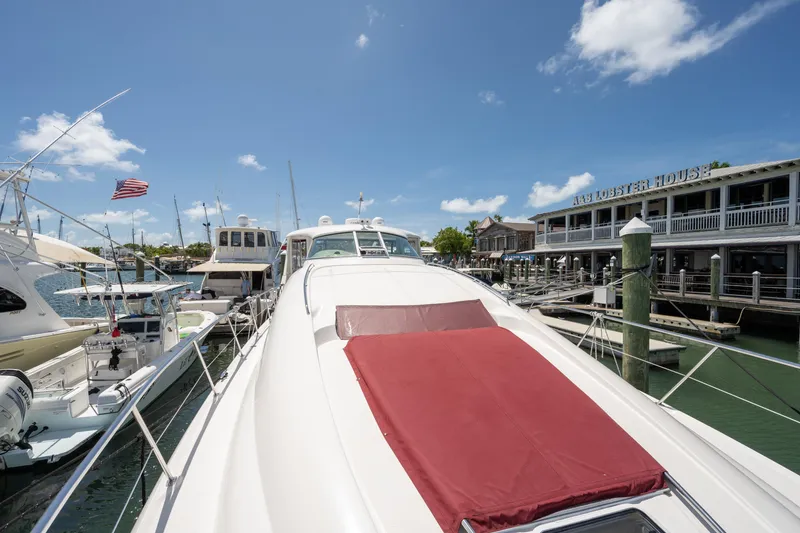 Slide: The Image of 2003 Sea Ray 480 Motor Yacht docked near a waterfront restaurant under a clear blue sky. - 12
