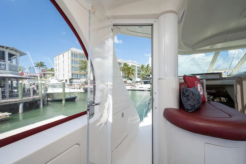 Slide: The Image of 2003 Sea Ray 480 Motor Yacht interior with marina view, featuring red seating and decorative pillows. - 22