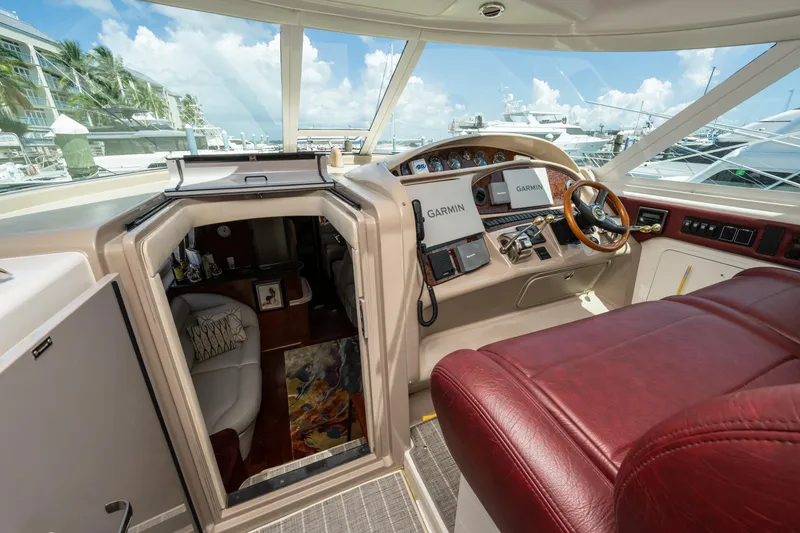 Slide: The Image of 2003 Sea Ray 480 Motor Yacht helm with Garmin navigation, luxurious seating, and cabin entrance. - 25