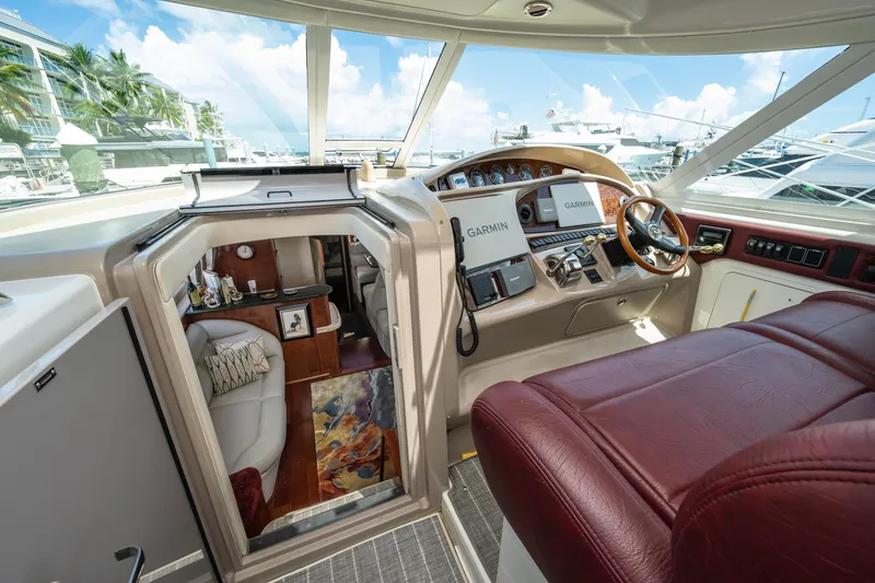 Slide: The Image of 2003 Sea Ray 480 Motor Yacht helm with Garmin navigation, luxurious interior, and marina view. - 26