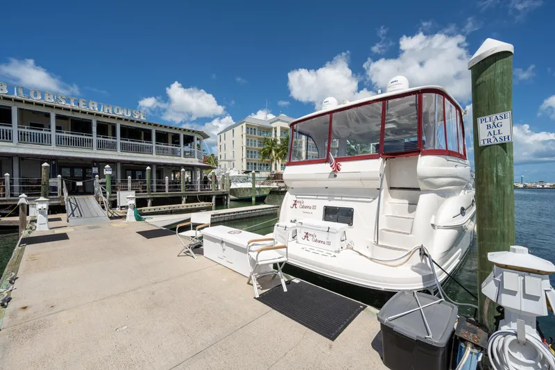 Slide: The Image of 2003 Sea Ray 480 Motor Yacht docked near a waterfront restaurant under a clear blue sky. - 8