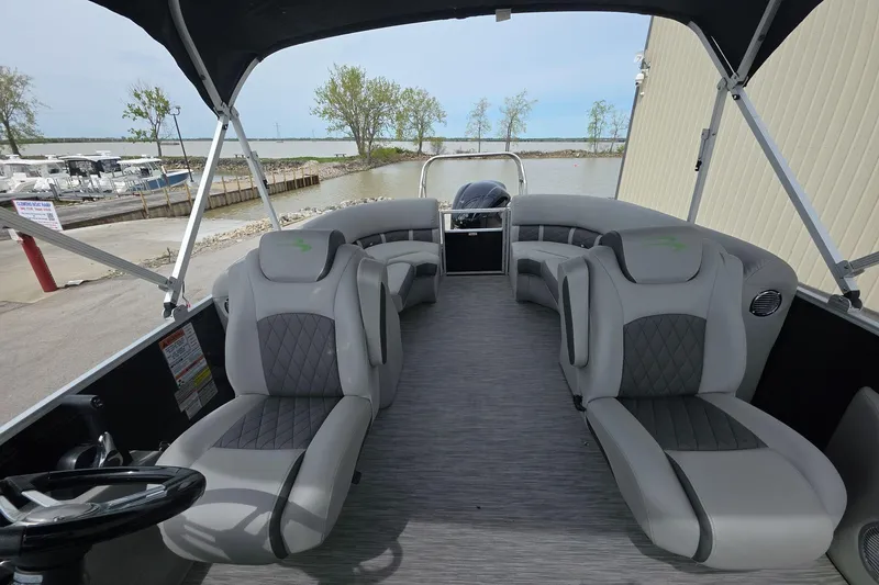 Slide: The Image of 2021 Bennington LX 24 Quad Bench pontoon boat interior with gray seating and steering wheel. - 10