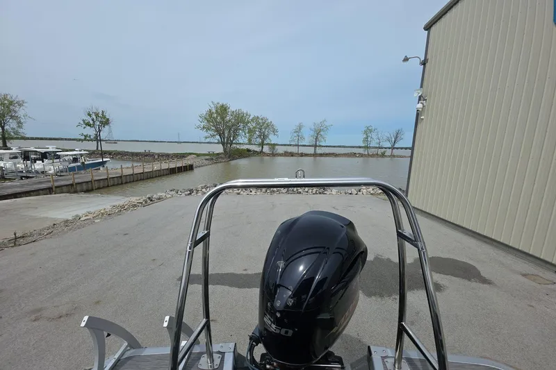Slide: The Image of 2021 Bennington LX 24 Quad Bench boat at a lakeside dock with trees and water. - 12
