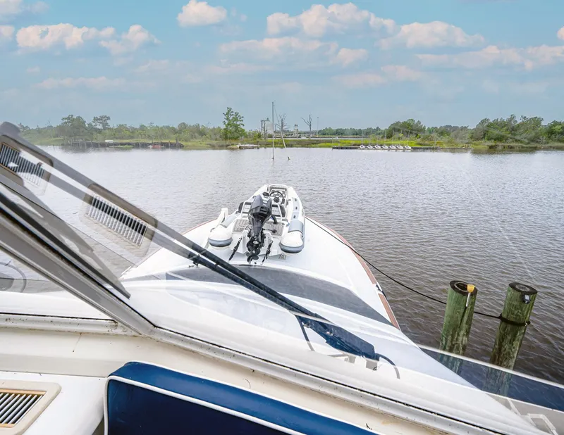Slide: The Image of 1997 Ocean Yachts 60 Super Sport EB cruising on a serene river under a blue sky. - 4
