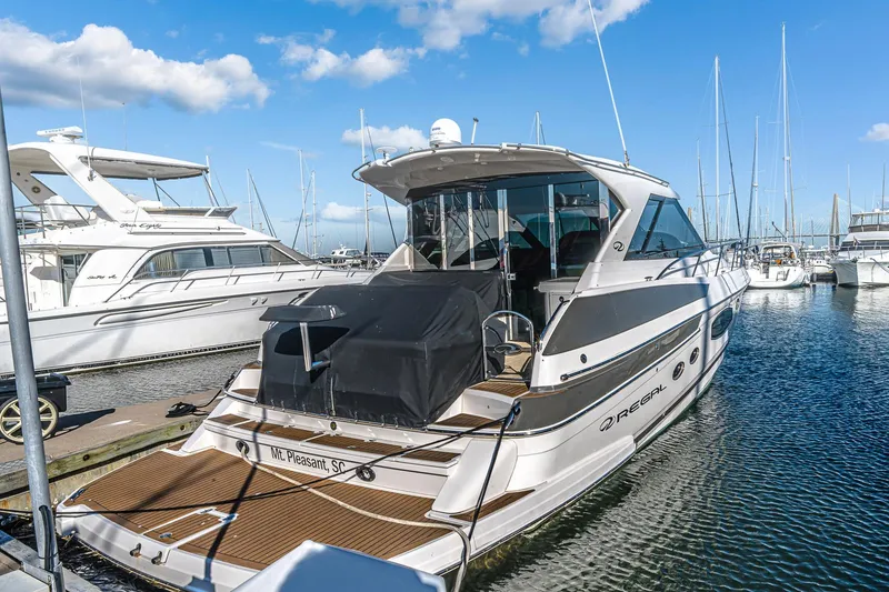 Slide: The Image of 2016 Regal 46 Sport Coupe yacht docked at marina under blue sky. - 10