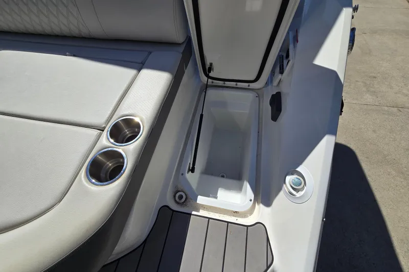 Slide: The Image of 2022 Sea Ray SLX 280 boat interior with open storage compartment and cup holders. - 22