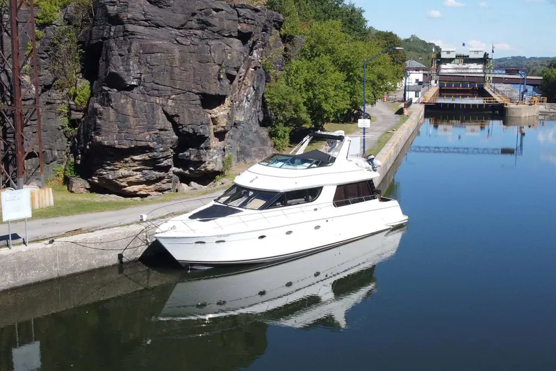 The Image of 1999 Carver 530 Voyager Pilothouse yacht docked by rocky shoreline. - 2