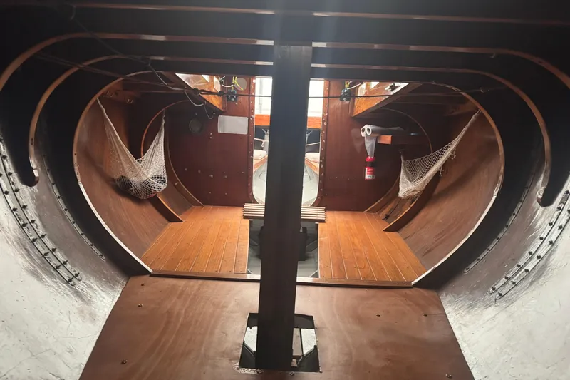 Slide: The Image of Interior of a 1944 Luders 24 sailboat, showcasing wooden flooring and storage nets. - 12
