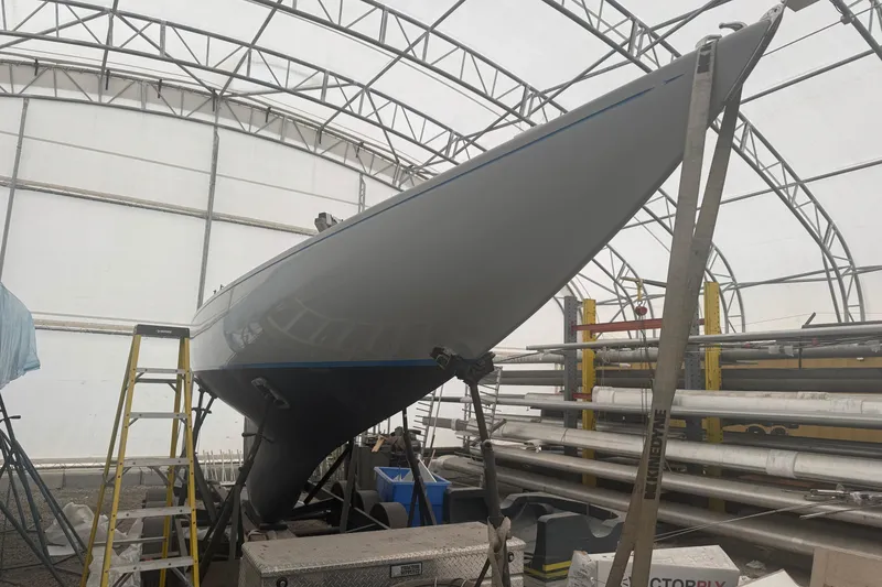 Slide: The Image of Restored 1944 Luders 24 sailboat in a workshop, showcasing sleek hull design. - 13